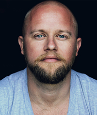 man with blond hair and beard in blue shirt