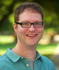 A middle aged man with glasses smiles at the camera.