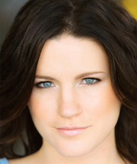 A woman with dark hair and blue eyes looks at the camera.
