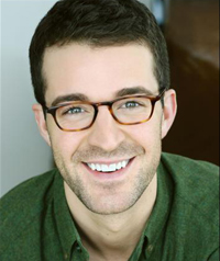 A man with glasses smiles at the camera