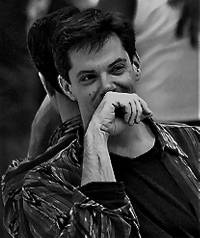 A black and white photo of a man covering his face while smiling.