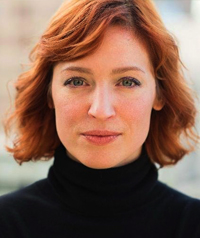 A woman in a black turtleneck smiles at the camera