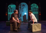 two actors sitting on boxes across fro each other and talking