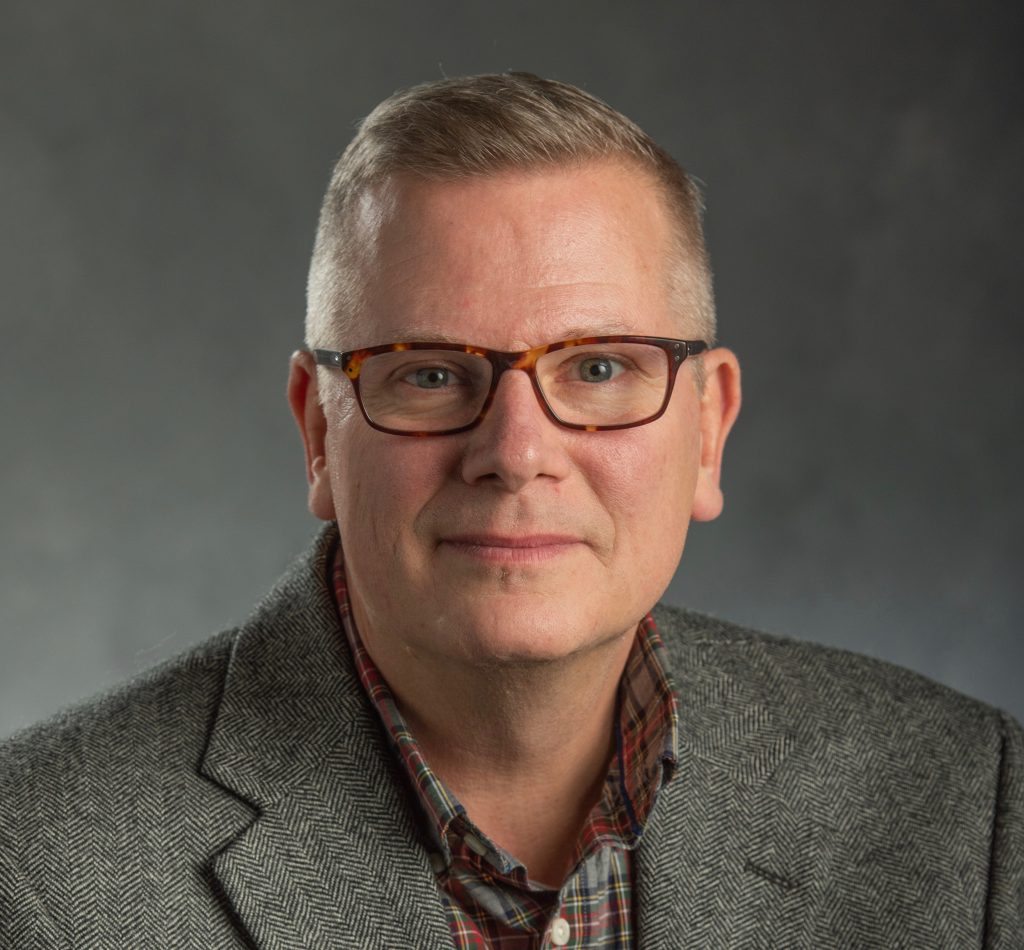 man wearing glasses and a gray jacket