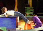 actor strapped to a table while another actor in on the ground