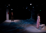 two actors standing on opposite sides of the stage talking, lights are shining on them individually in darkness