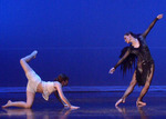 two female dancers, one is standing with arms diagonally while the other is on the ground with one leg up