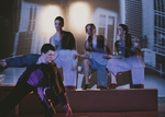 three dances sitting on a porch, another actor is sliding in from the left