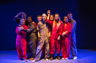 group of actors in jumpsuits looking determined at the camera