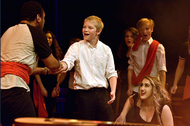 actor shaking hands with another, other actors are watching
