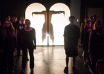 silhouette of an actor doing a handstand, more actors are standing on the left and right sides of the silhoutte