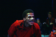 actor leaning forward and smiling into the audience