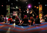 actors sitting criss-cross looking out toward the back of the stage