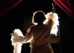 back of an actor with a fluffy, white scarf and waving