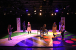 actors standing around a stage projected with pattens of different shapes