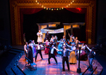 group of actors dancing and singing on a set that looks like a wedding venue
