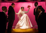 actor dressed as bride posing as male actors watch
