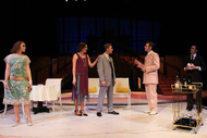 an actor talking to a couple in front of a couch