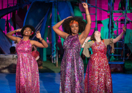 tree actors in sequined dresses dancing and posing