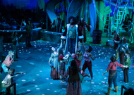 dimly lit blue set, and actor is elevated while all other actors are looking up in awe and admiration