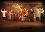 and actor grabbing the wrist of another with a renaissance photo as the background