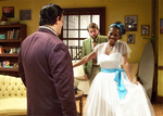 actor wearing a big, white dress while two other actors look