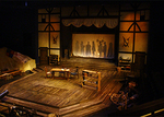 wooden set with two wooden tables with chairs, an image of people standing is projected in the background