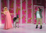 blonde flipping her hair while accompanied by a dog, anothe actor is standing and posing to the right