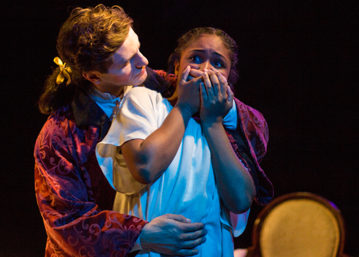 an actor holding another from behind, the actor being held has he hands over her mouth in fear