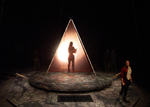 actor standing onstage with a lit up silhouette in the background