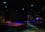 stage with two different sets, there are blue and green lights streaking the stage