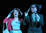 two actors looking upward while holding newspaper on their head