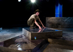 actor crouched on top of a stone slab