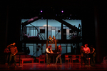 set of a house, characters are paired off and having their own discussions in a dimly lit setting