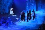 actors standing on an ice cliff while a crowd looks up to them