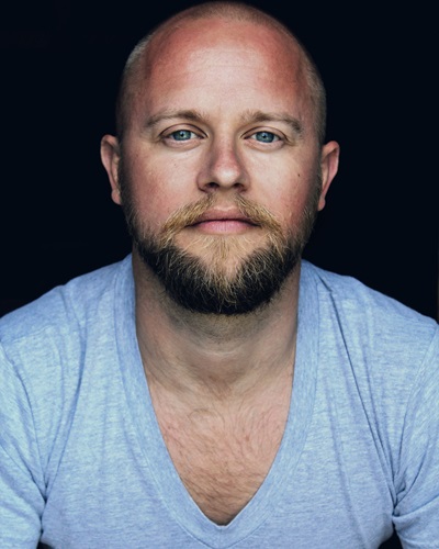 man wearing a blue t shirt staring straight at the camera