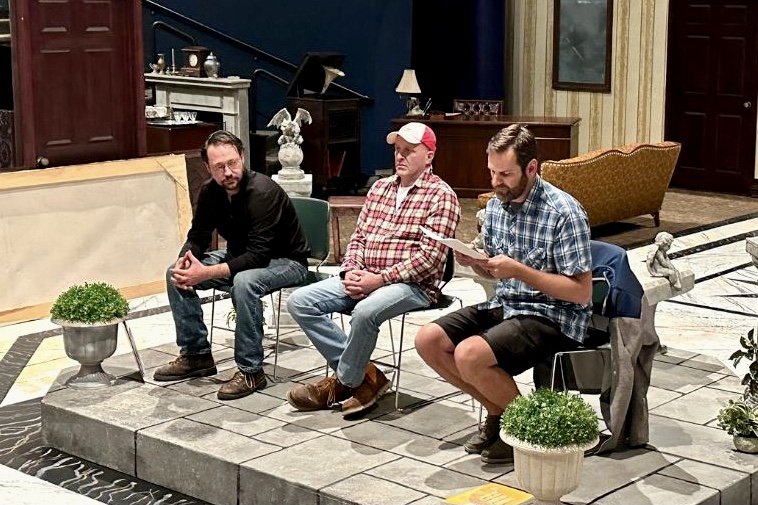 A photo of three people sitting in chairs on a raised floor.