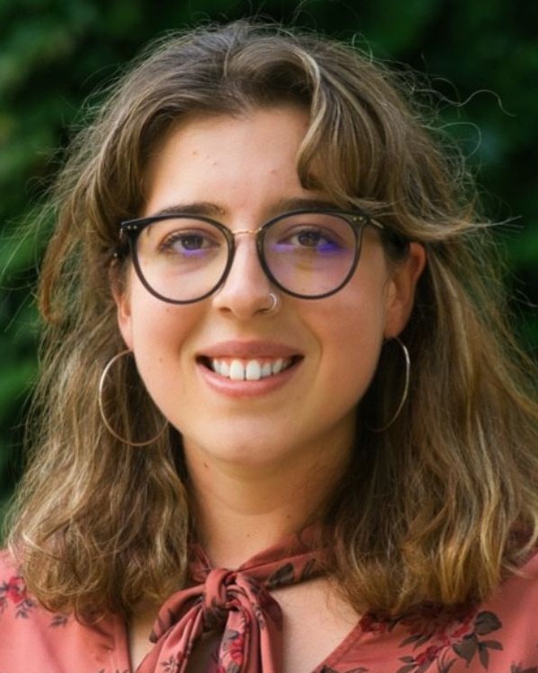 A picture of a person with long blond hair and glasses smiling