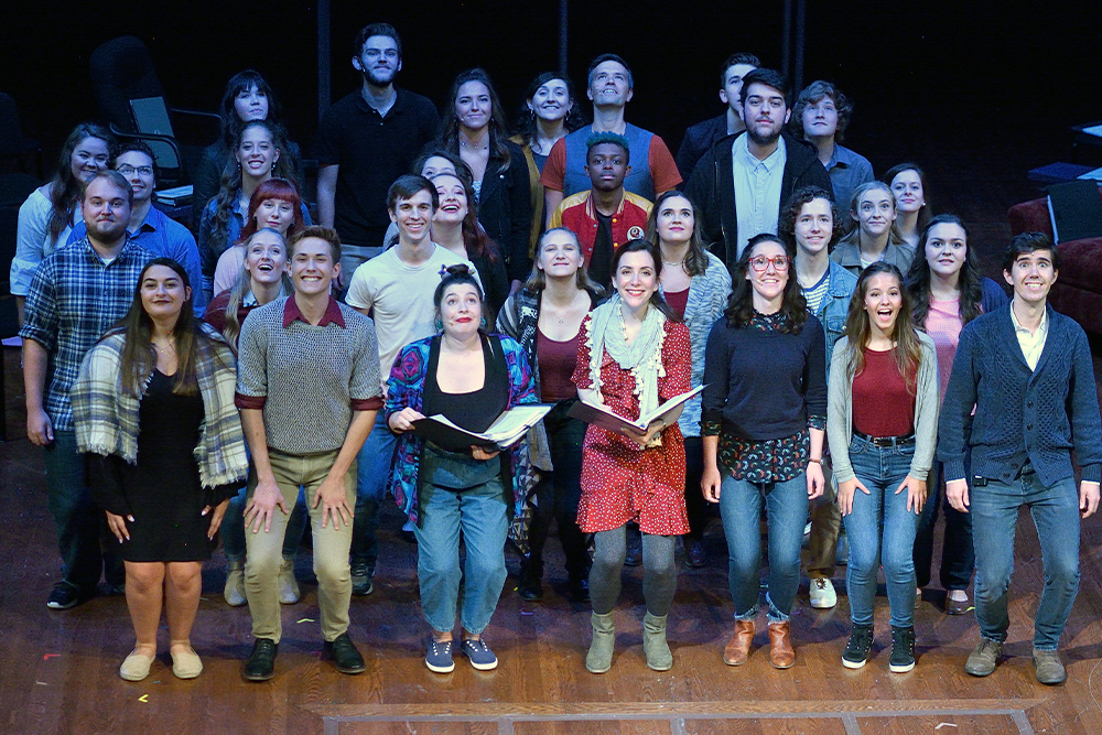 A group photo on stage of the cast of actors in a theatre production.