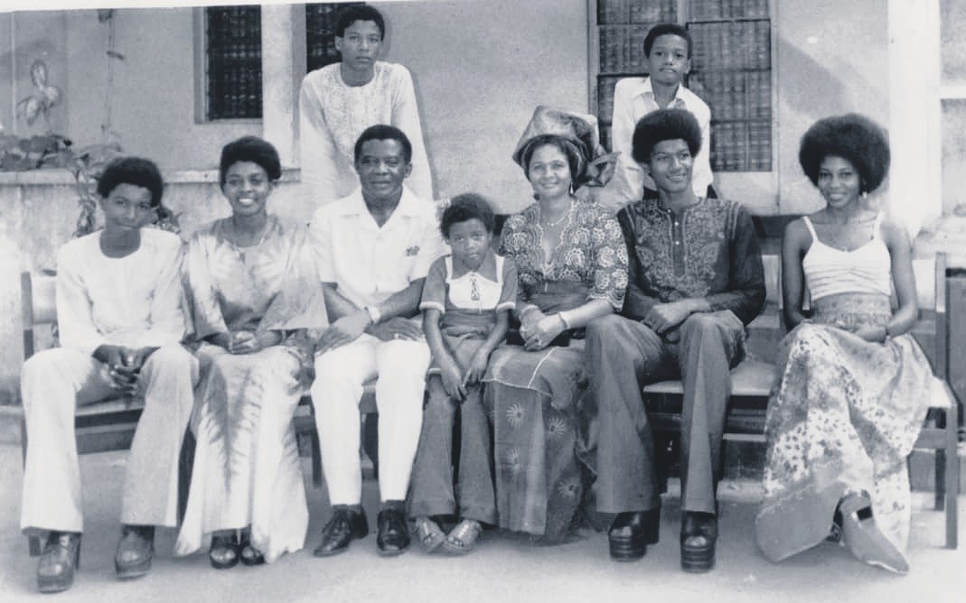 A black-and-white historical photograph of the Effiong family in Enugu during the 1970s. The family of ten is posed in two rows; Philip Effiong as a young man stands in the back row on the far left.