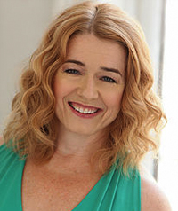 A woman in a turquoise top smiles at the camera