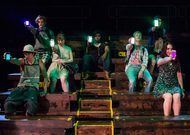 actors sitting and shining phone lights toward the audience