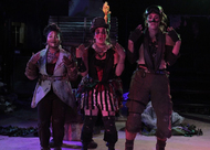 three actors hold both arms up with bent elbows with painted faces and steampunk clothing