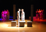 two actors staring at one another in the center of the lit stage