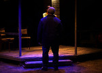 actor standing in the dark with back towards the audience