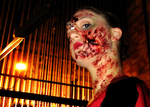 an actor looking down at the camera, she has bloodied scars and splatters all over her face and neck