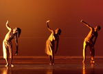 three dancers standing with their right hand held up to shield their face from the light