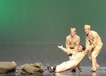 two dancers dressed dressed as soldiers dragging a comrade 
