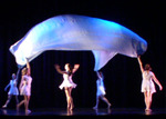 dancers fluttering up a large cloth with a dance underneath