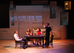 three actors at a dining table lecturing a fourth actor at the end of the table